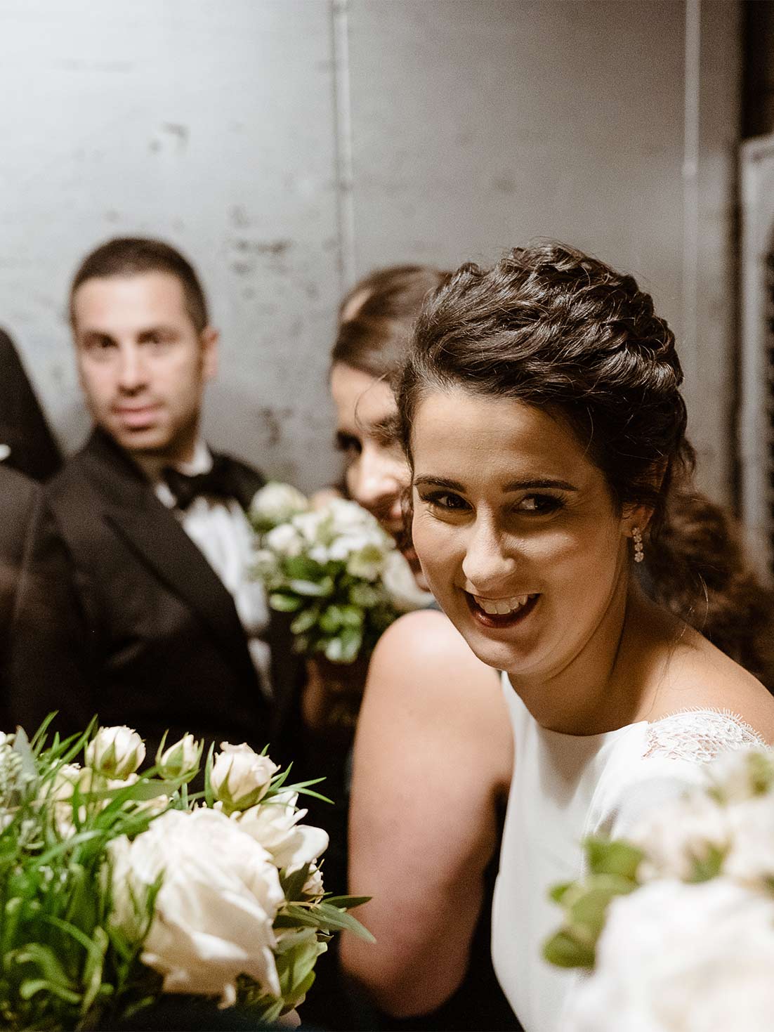 Bride smiles as bridal party rides in an industrial service freight to enter the westchester wedding venue